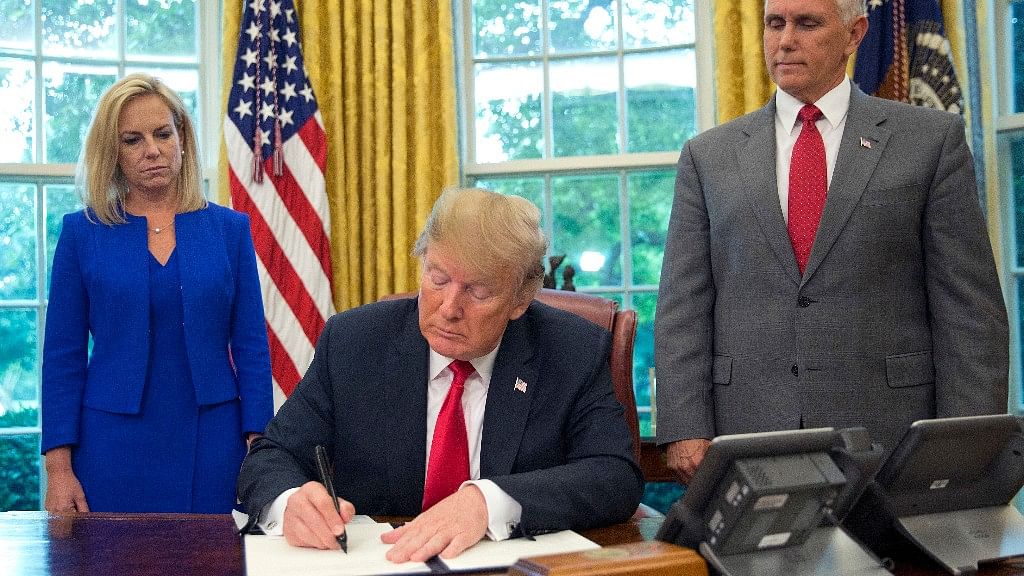President Donald Trump signs an executive order to keep families together at the border, but says that the ‘zero-tolerance’ prosecution policy will continue, during an event in the Oval Office of the White House in Washington. Standing behind Trump are Homeland Security Secretary Kirstjen Nielsen, left, and Vice President Mike Pence