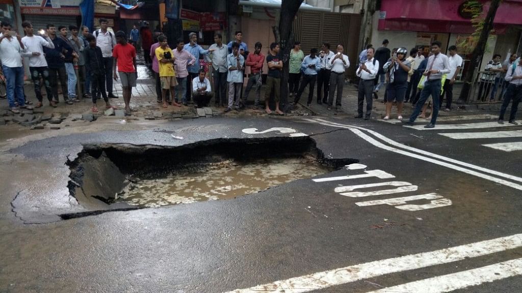 A road leading to Metro Cinemas caved in in Mumbai’s Kalbadevi area after a pipeline burst due to heavy rains outside Gol Masjid on Monday, 24 June.