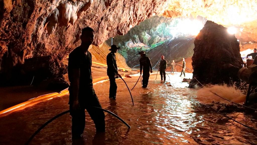 Thai rescue teams arrange water pumping system at the entrance to a flooded cave complex where 12 boys and their soccer coach were trapped.