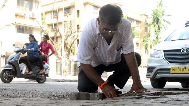 Dadarao Bilhore filling up a pothole in Mumbai.