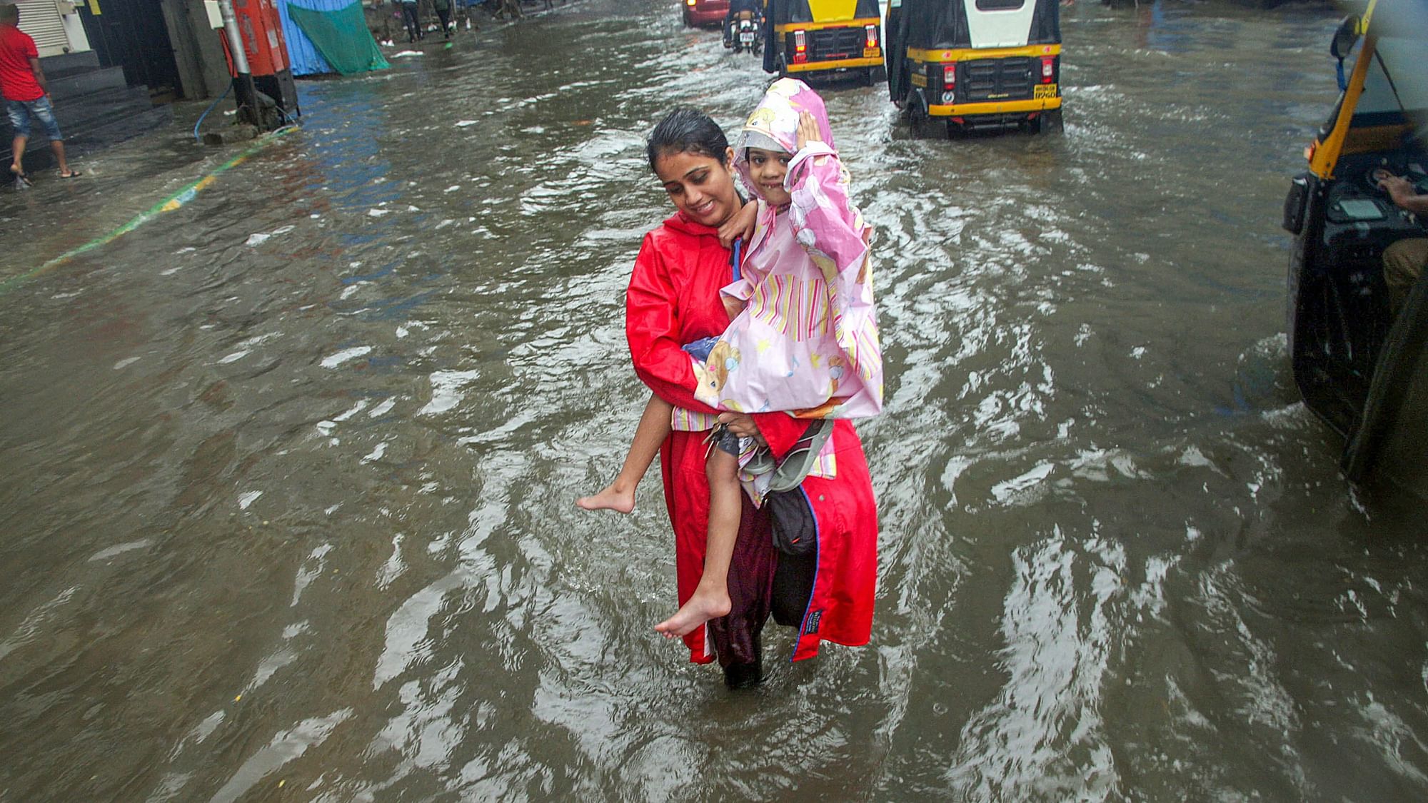 A mother carries her child in a water-logged street of Mumbai