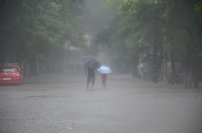 Mumbasi: People shield themselves with umbrellas as heavy rains lash Mumbai, on July 10, 2018. (Photo: IANS)