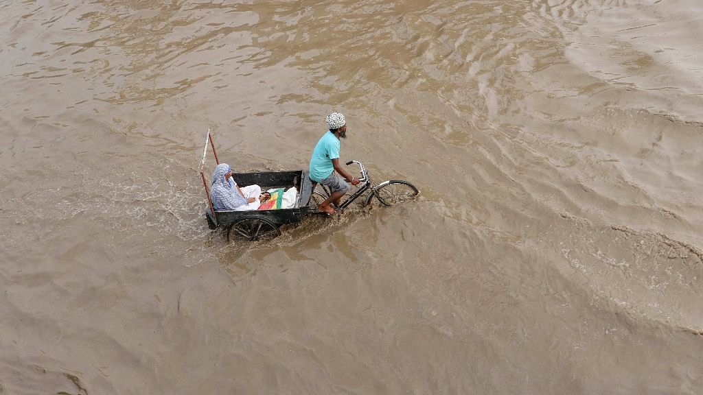A rickshaw-puller carries an elderly woman through flood waters after rains, in Patiala on Monday, 16 July 2018.