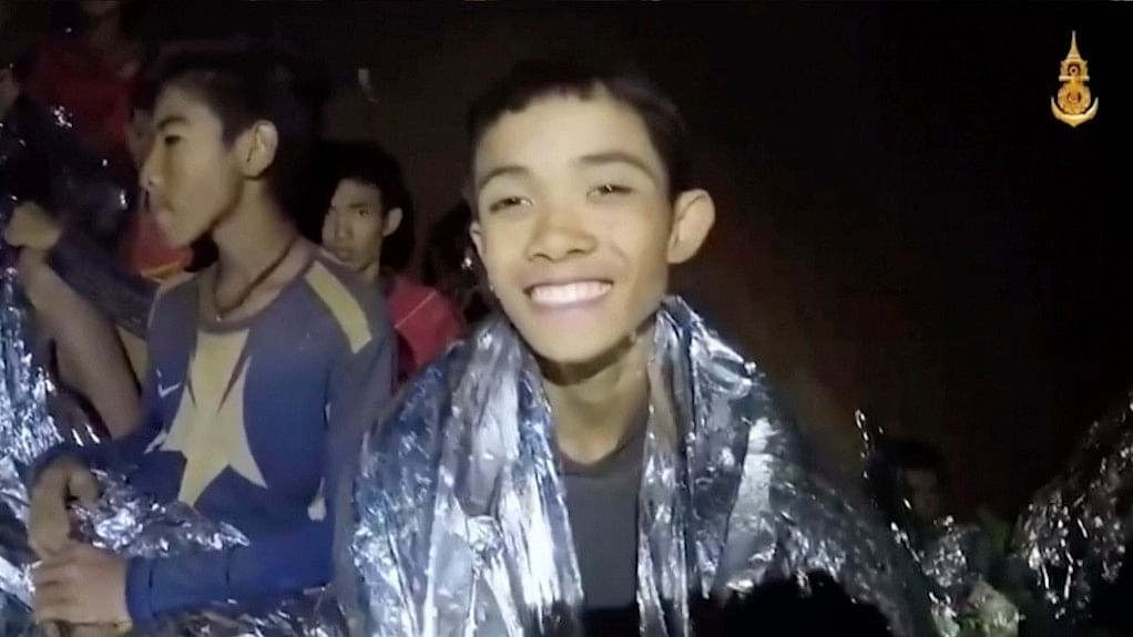 In this image taken from video provided by the Royal Thai Navy Facebook Page, a Thai boy smiles as Thai Navy SEAL medic help injured children inside a cave in Mae Sai, northern Thailand.
