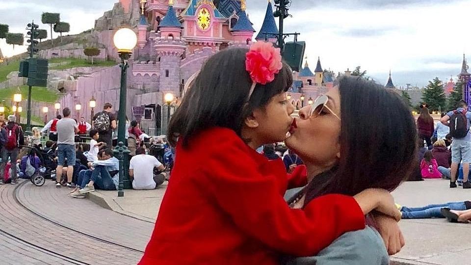 Aishwarya Rai Bachchan kisses her daughter, Aaradhya against the backdrop of Disneyland in Paris.