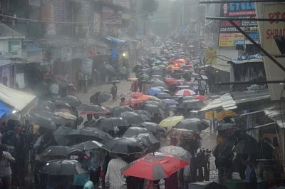 Mumbai: People shield themselves with umbrellas as they walk through the flooded streets during heavy rains, in Mumbai on July 10, 2018.(Photo: IANS)