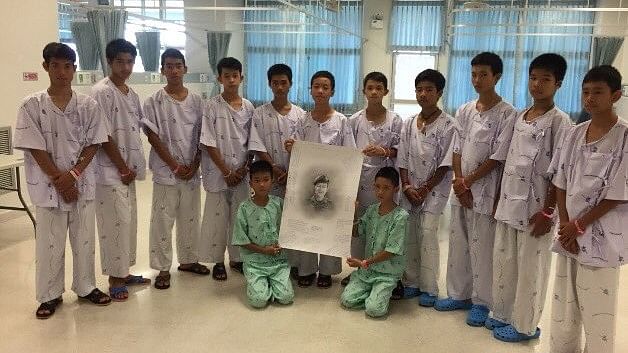 The soccer team of 12 boys posing with a portrait of the Thai Navy SEAL who died while rescuing them from a Thai cave.&nbsp;