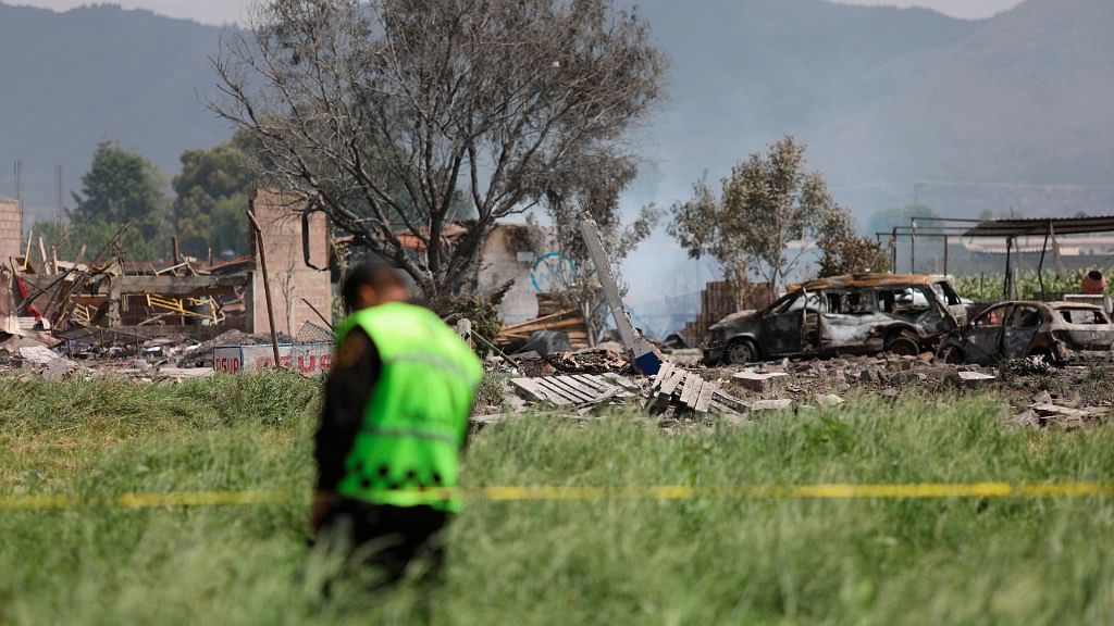 A police officer guards the perimeter around the wreckage of several fireworks workshops in Tultepec on Thursday, 5 July.