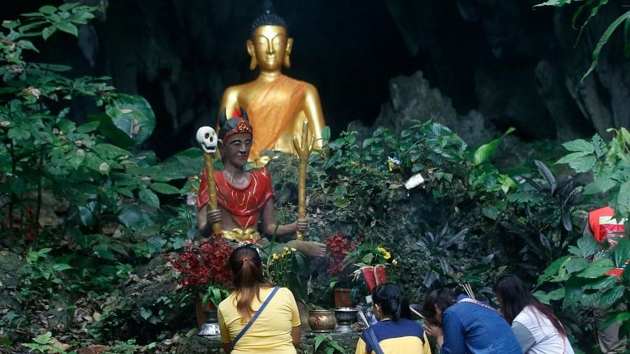 Family members pray in front of a Buddhist statue near the cave where 12 boys and their soccer coach had been trapped.&nbsp;