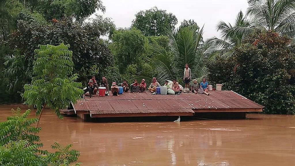 People on the roofs of houses that are submerged  with flood waters in southern Laos.