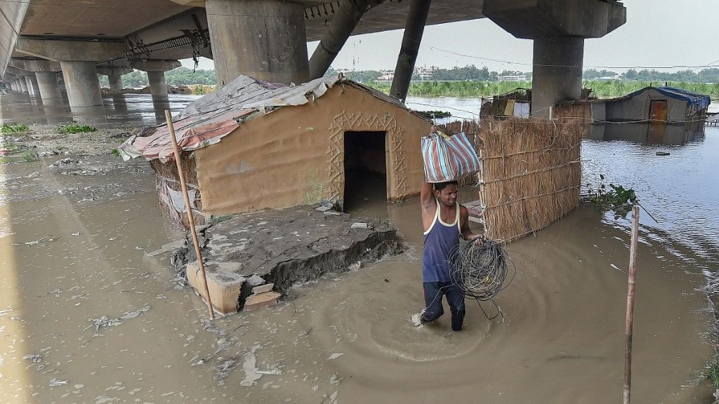  A man shifts from his submerged shanty at Yamuna Khadar after the water level of Yamuna river rises, in Delhi on 29 July.