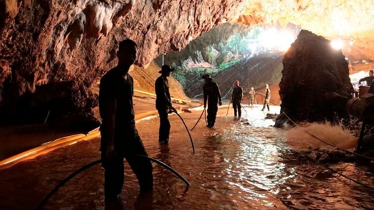 Thai rescue teams arrange a water pumping system at the entrance to the flooded cave complex.