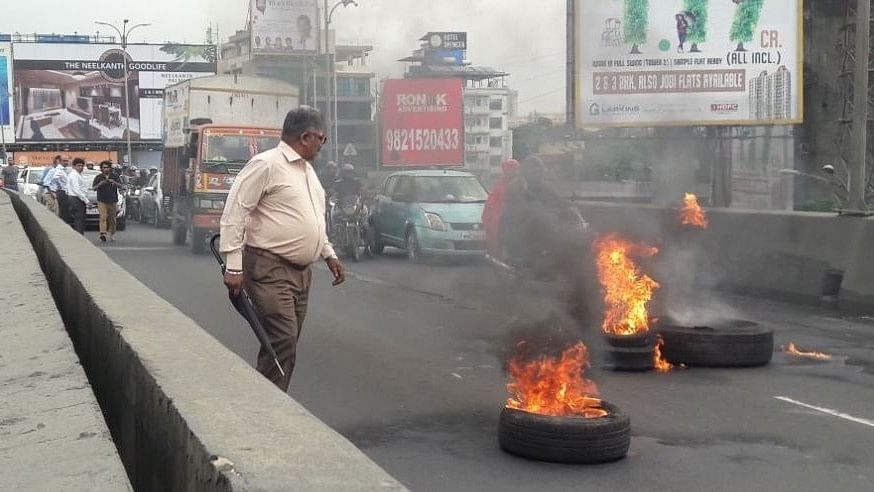 Protestors set tyres on fire on the Majiwada bridge in Thane on 25 July.