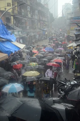 Mumbai: People shield themselves with umbrellas as they walk through the flooded streets during heavy rains, in Mumbai on July 10, 2018.(Photo: IANS)