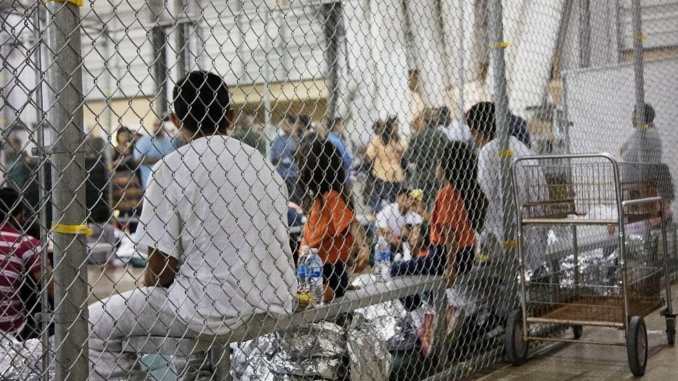 File photo of people in custody related to cases of illegal entry into the United States, sit in one of the cages at a facility in McAllen, Texas.