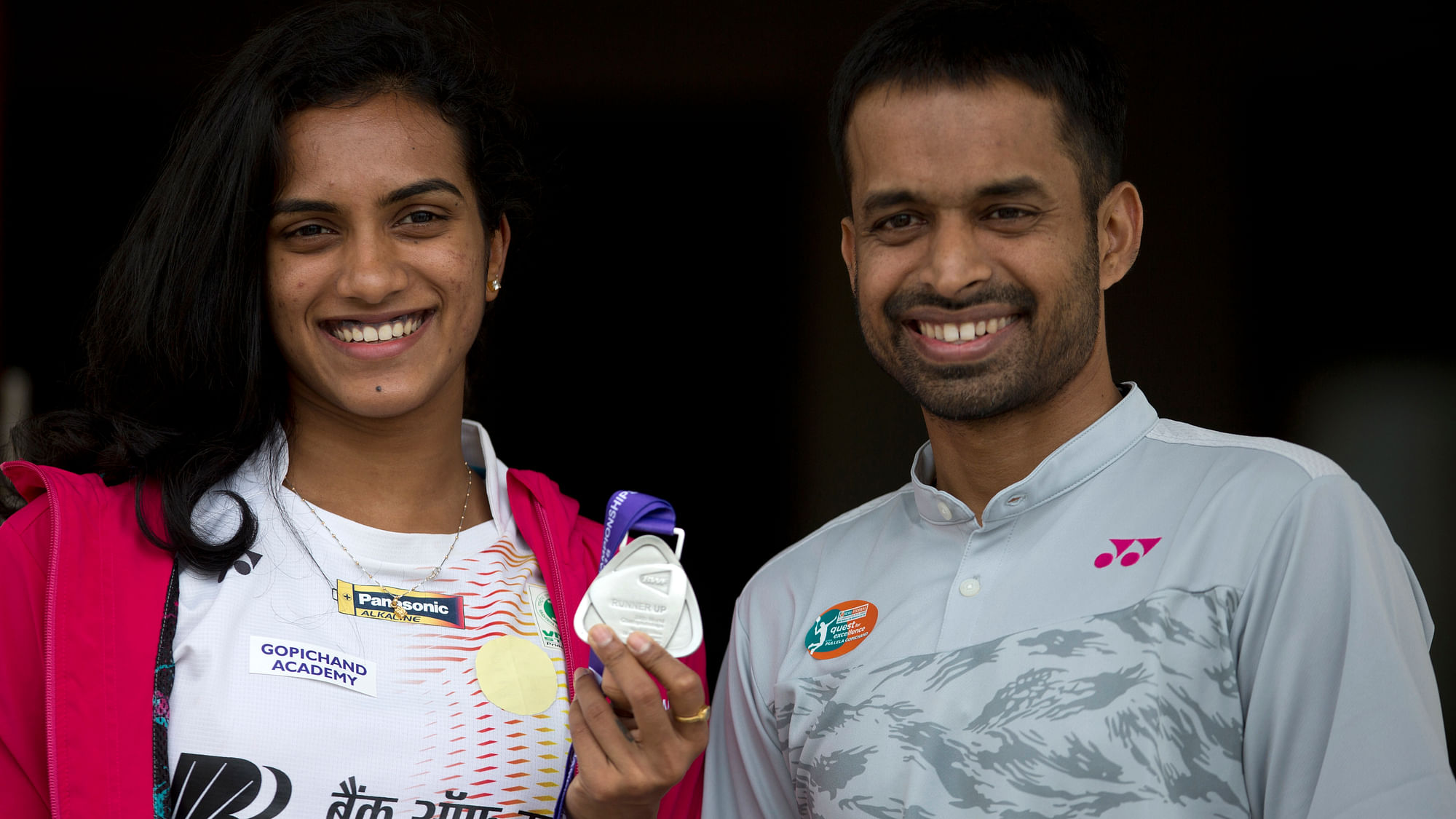 Indian Badminton player P. V. Sindhu displays her medal, with her coach Pullela Gopichand standing beside her, during a press conference in Hyderabad, India, Tuesday, Aug. 7, 2018. Sindhu won the silver medal at the BWF World Championships in Nanjing, China.