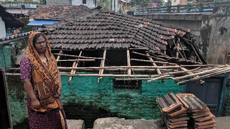 A woman poses in front of a damaged house in Palakkad, Kerala.&nbsp;