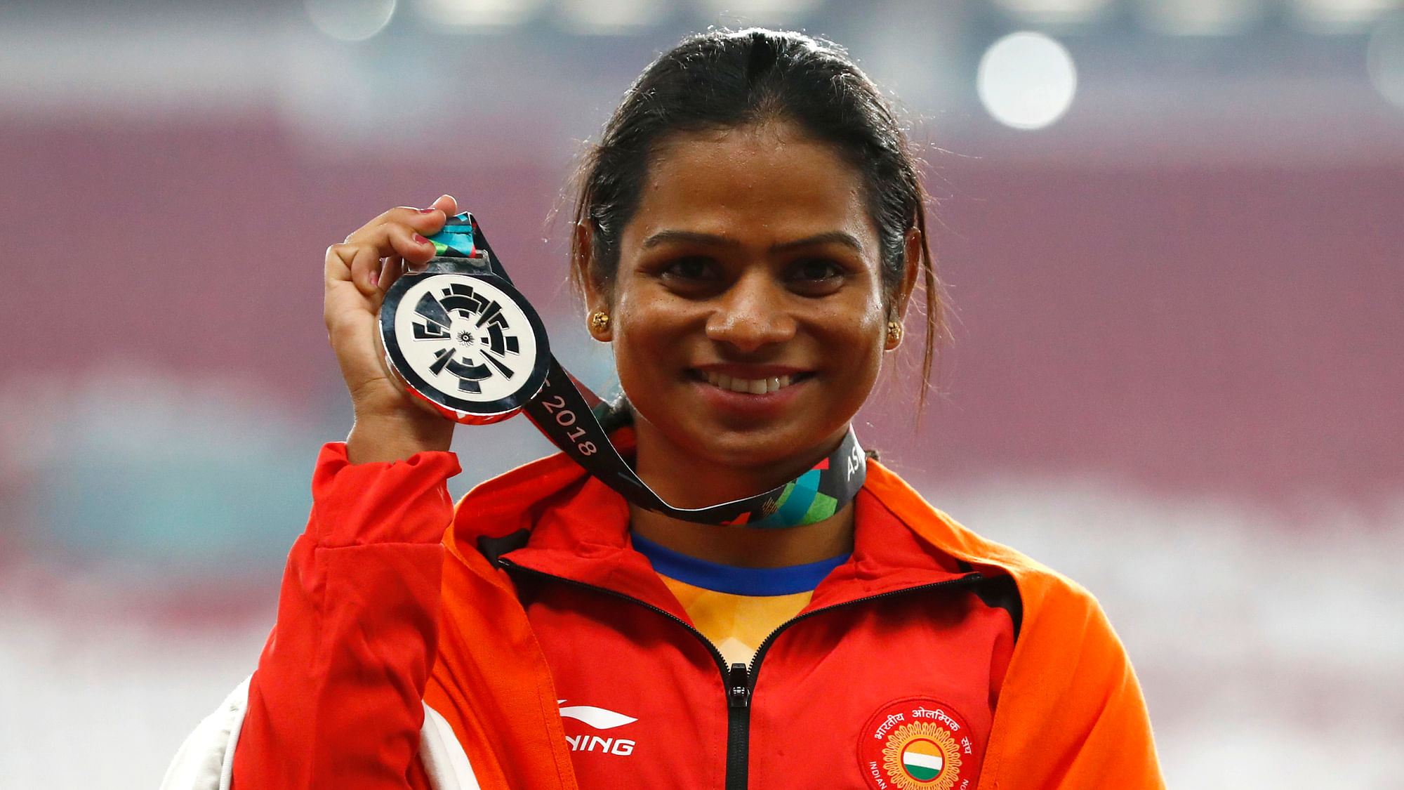 India’s Dutee Chand celebrates on the podium after winning the silver medal in the women’s 100m final during the athletics competition at the 18th Asian Games in Jakarta, Indonesia.
