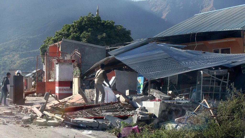 Indonesian men inspect buildings damaged by earthquake in Sembalun, on Lombok Island, Indonesia