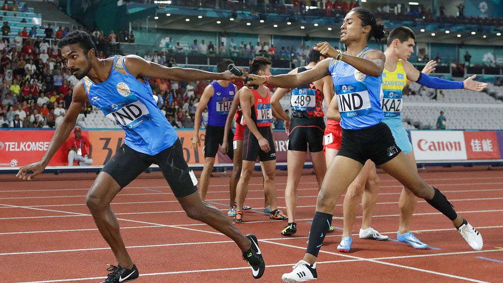 Hima Das, right, hands the baton to teammate Arokia Rajiv during the 4x400m mixed relay final.