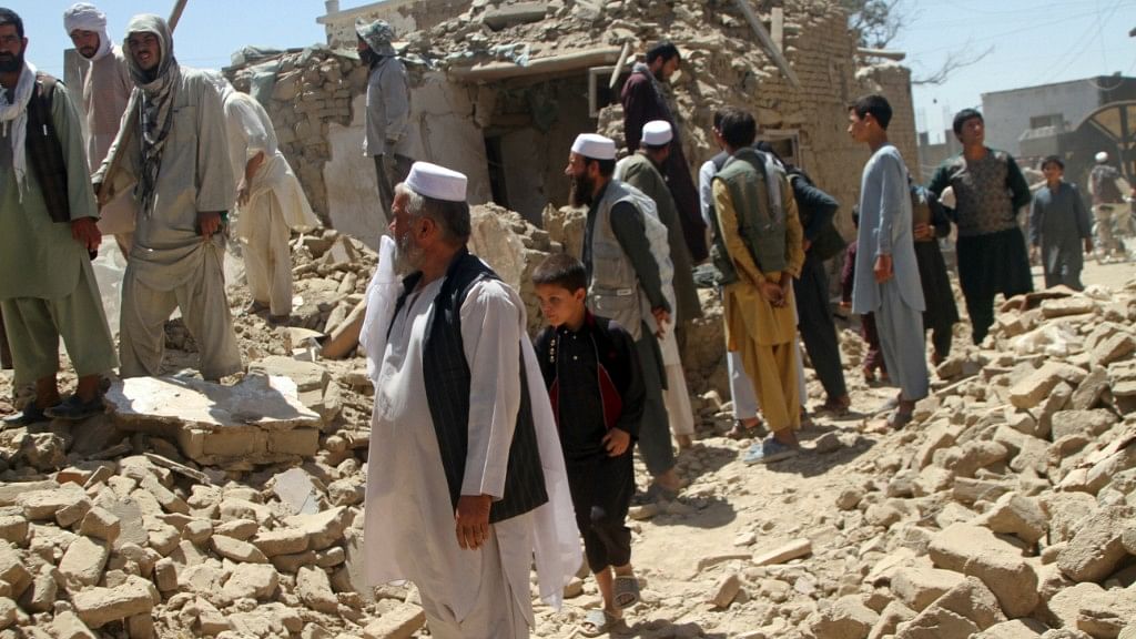Afghan men stand near a damaged house following a Taliban attack in Ghazni, Afghanistan