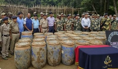 Sepahijala: Security personnel present before press 3,350 kg of dry cannabis (ganja) valued over Rs 2 crore and the two persons arrested by them in Sepahijala district in west Tripura on Aug 3, 2018. The contraband was buried underground in 85 drums in a betel-leaf garden and was recovered after a 15-hour operation. (Photo: IANS)