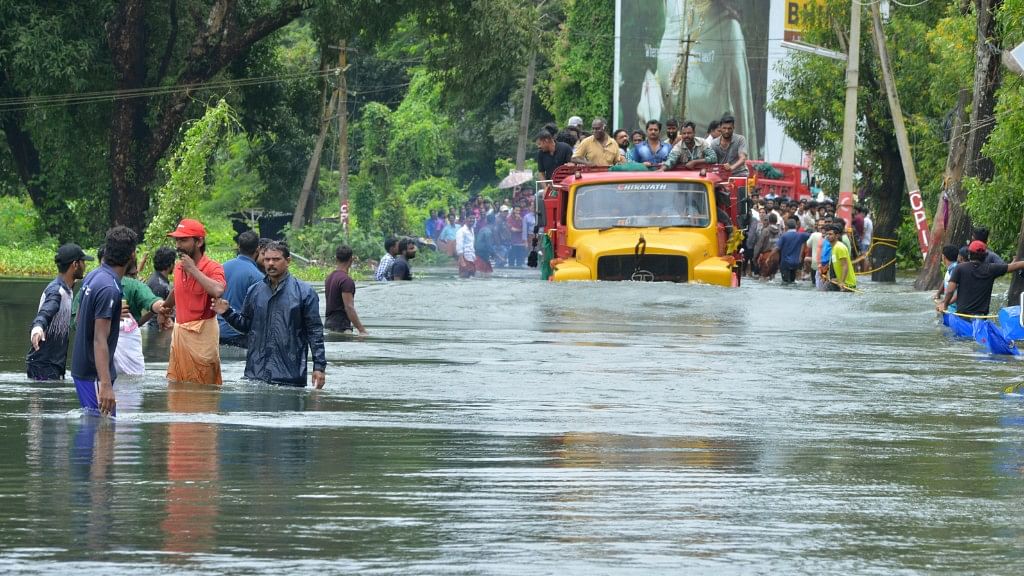 A truck carries people past a flooded road in Thrissur in Kerala on Saturday, 18 August.