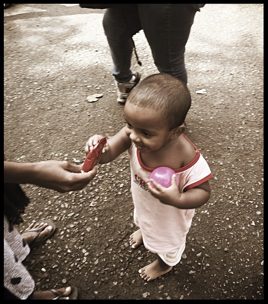 Two-year-old Amaya taking a chocolate from his mother Sunita. 