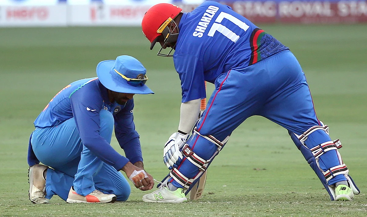 India’s Dinesh Karthik, left, ties shoelaces of Afghanistan’s Mohammad Shahzad during the one day international cricket match of Asia Cup between India and Afghanistan.