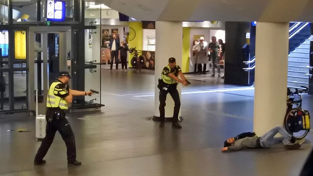 Dutch police officers point their guns at a wounded 19-year-old man who was shot by police after stabbing two people in the central railway station in Amsterdam, the Netherlands.