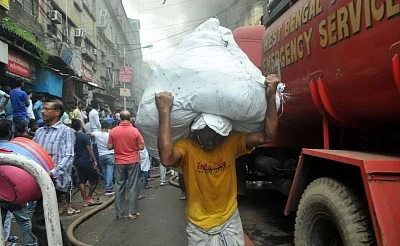 Kolkata: A man carries a sack to safe place from Bagri Market where a massive fire broke out around 2.45 a.m. in Kolkata on Sept 16, 2018. (Photo: Kuntal Chakrabarty/IANS)