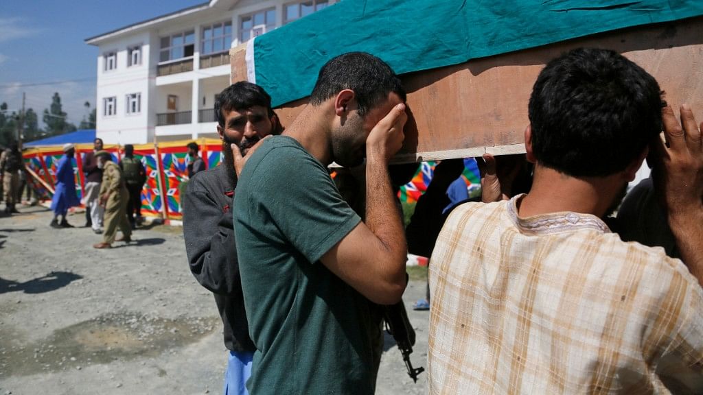 An unidentified man cries as he carries the coffin of a relative, a slain policeman, during a wreath laying ceremony at a base camp at Shopian.