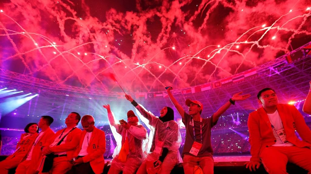 Athletes and volunteers look up to the illuminated sky at the closing ceremony at the Asian Games.