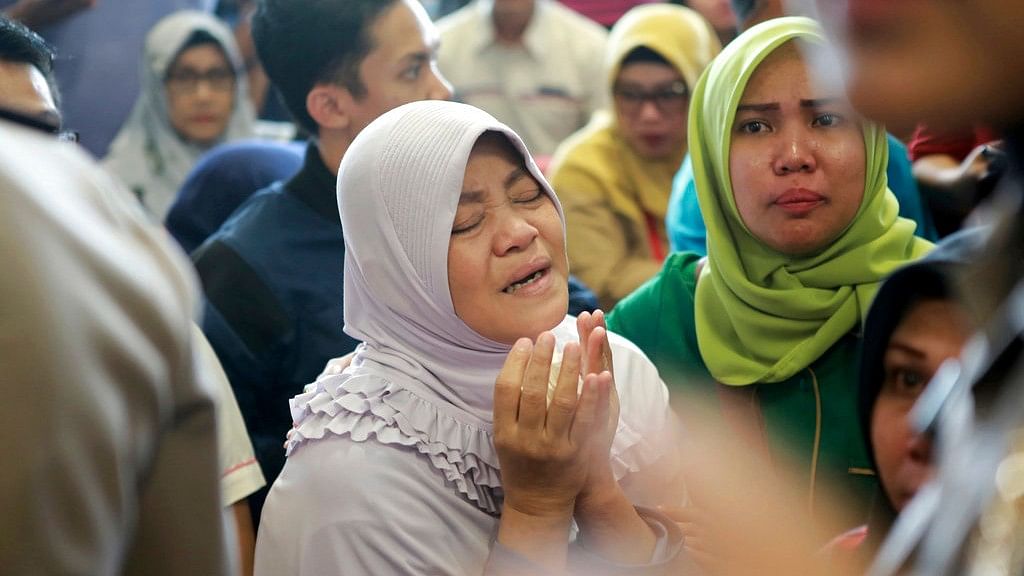 A relative of passengers prays as she and others wait for news on a Lion Air plane that crashed off Java Island, at Depati Amir Airport in Pangkal Pinang, Indonesia, on Monday, 29 October 2018.