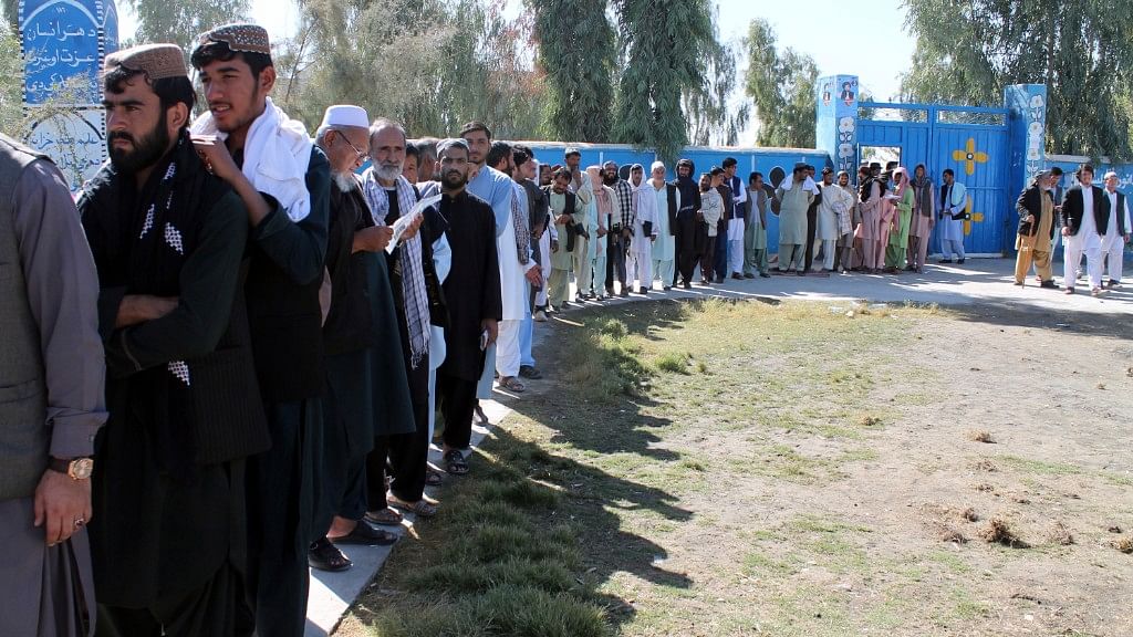 Afghan men line up to cast their votes, outside a polling station during the Parliamentary election in Helmand province, south of Afghanistan, Saturday, Oct. 20, 2018.