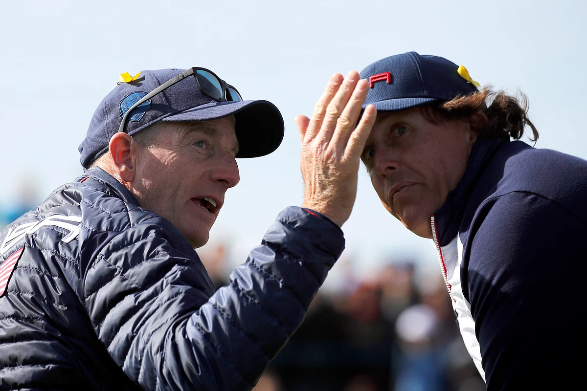 US team captain Jim Furyk gestures while speaking with his player Phil Mickelson during a fourball match on the second day of the 2018 Ryder Cup.
