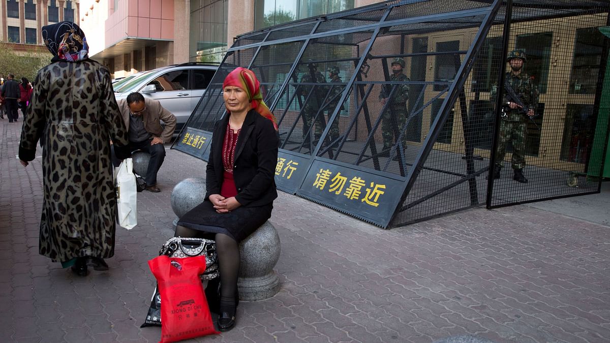  In this May 1, 2014, file photo, an Uighur woman rests near a cage protecting heavily armed Chinese paramilitary policemen on duty in Urumqi in China’s northwestern region of Xinjiang.&nbsp;