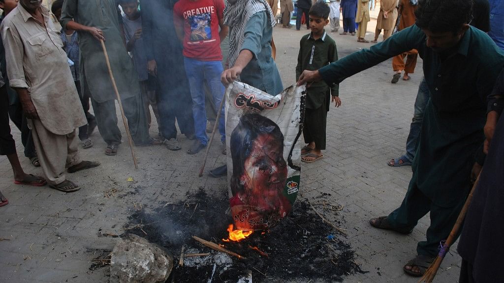 Pakistani protesters burn a poster image of Christian woman Asia Bibi, who has spent eight-years on death row accused of blasphemy and acquitted by a Supreme Court, in Hyderabad, Pakistan on Thursday, 1 November.
