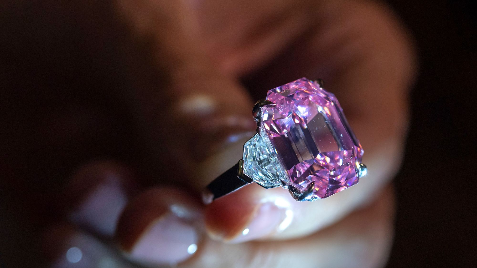 An auctioneer displays an 18.96-carat fancy vivid pink diamond.