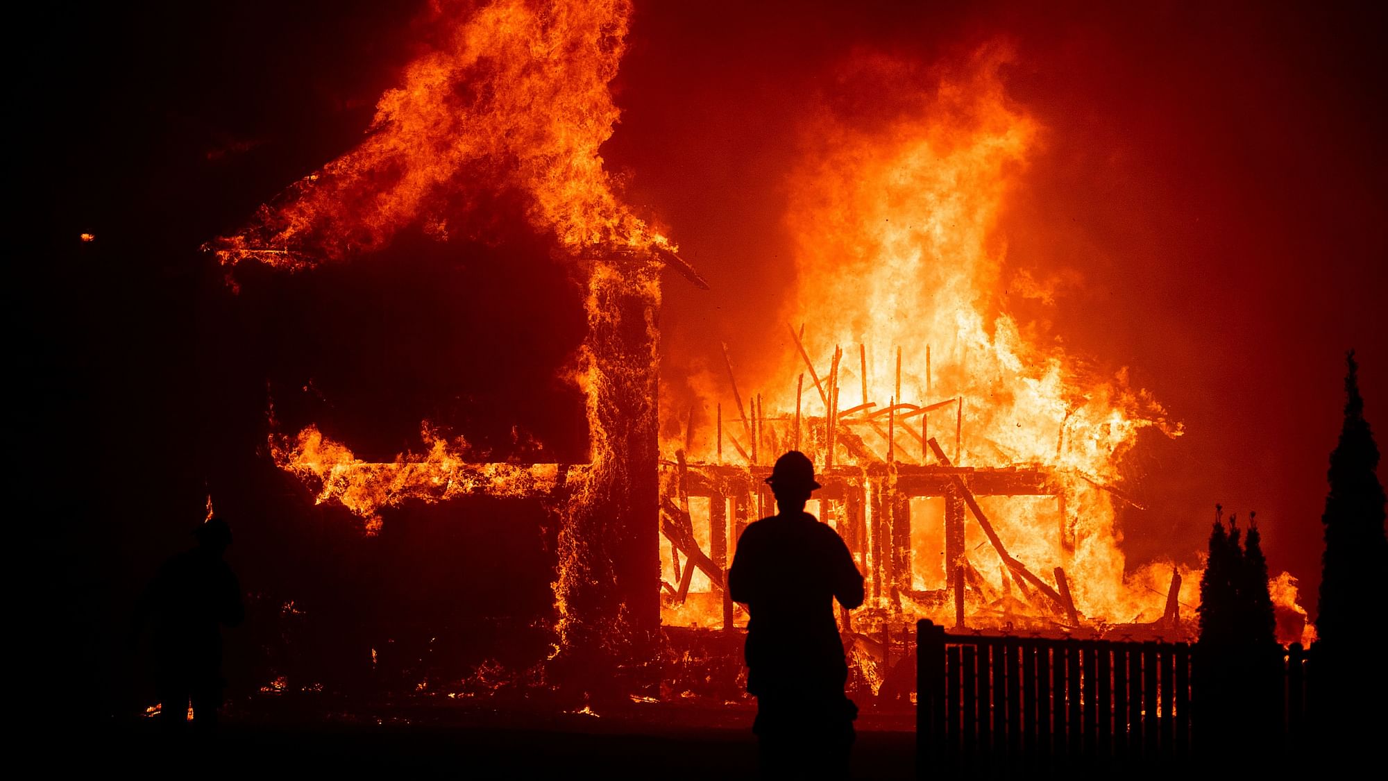 A firefighter looks on as a house gets completely burned down in the Paradise, California.