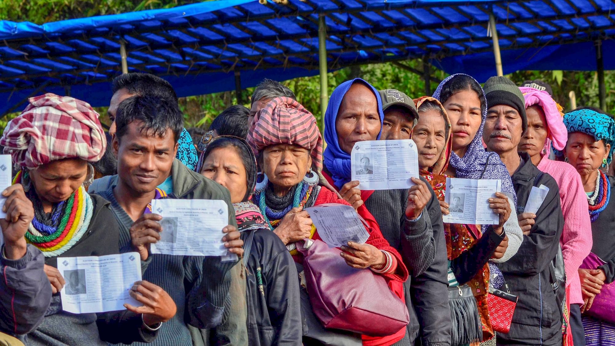 Voters show their identity card as they stand in a queue at a polling station during Mizoram Assembly elections on Wednesday, 28 November.