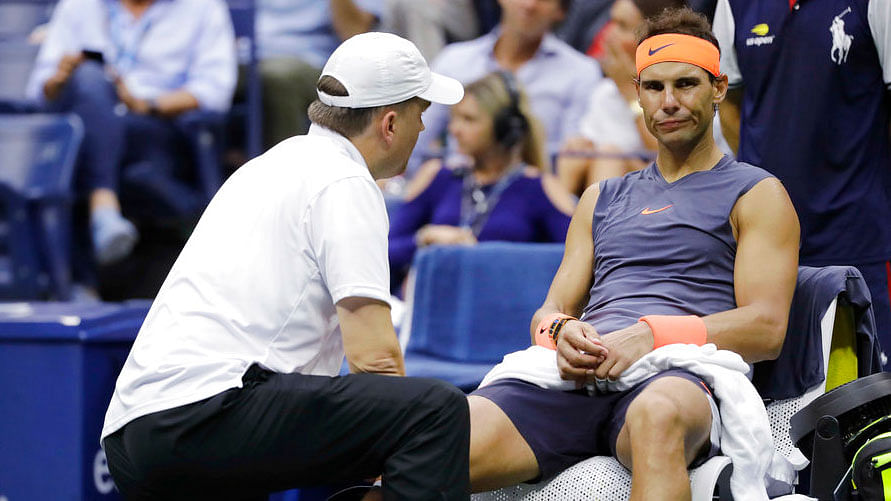 Rafael Nadal is treated by a trainer during the US Open semi-final.