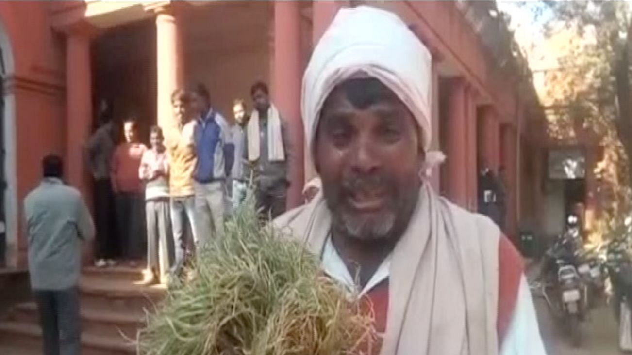 Madhya Pradesh farmer holds a clump of his destroyed crop outside  district collector’s office.