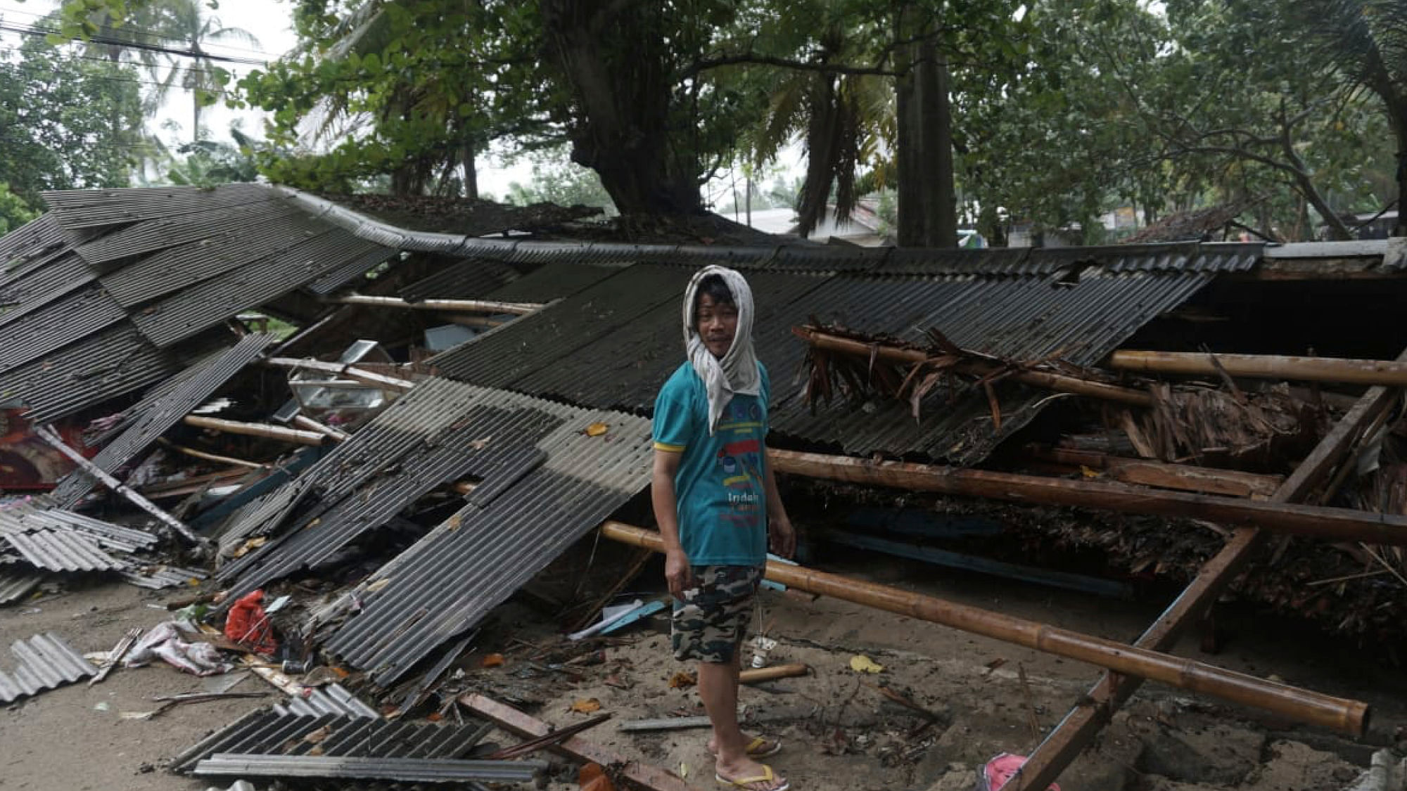 A man inspects his house which was damaged by the tsunami