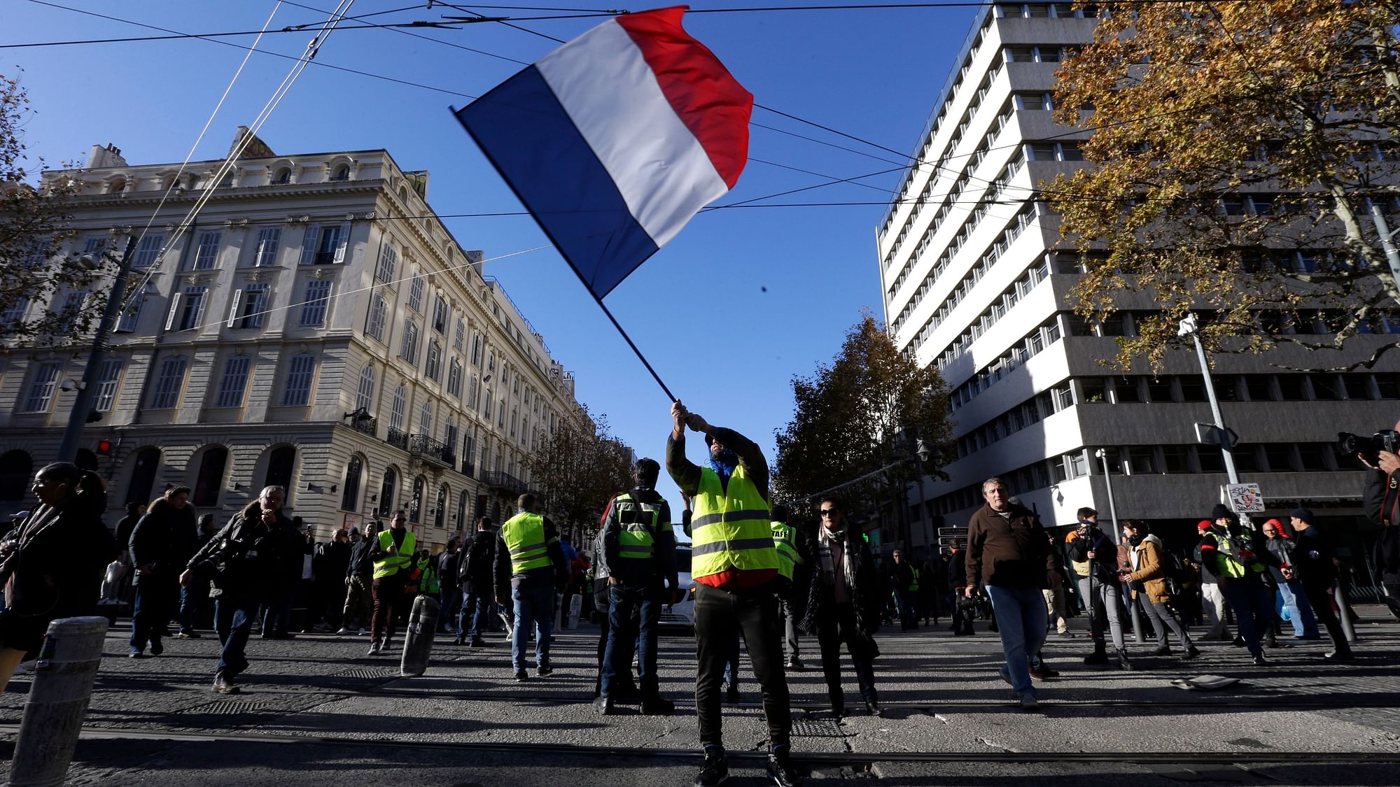 A demonstrator waves the French flag during a ‘Yellow Vest’ march on Saturday, 8 December, in Marseille, southern France.&nbsp;