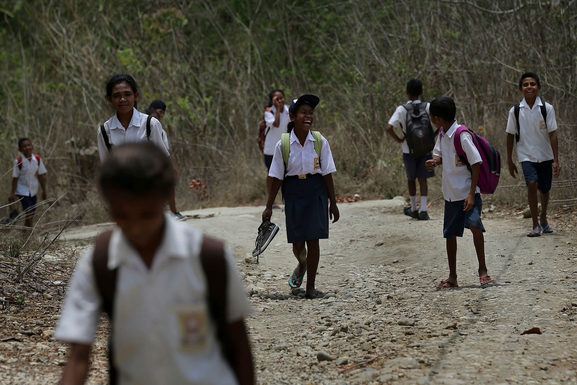  Students walk on a dirt road after school in West Timor, Indonesia. Children in this impoverished region of Indonesia often must walk long distances to school.