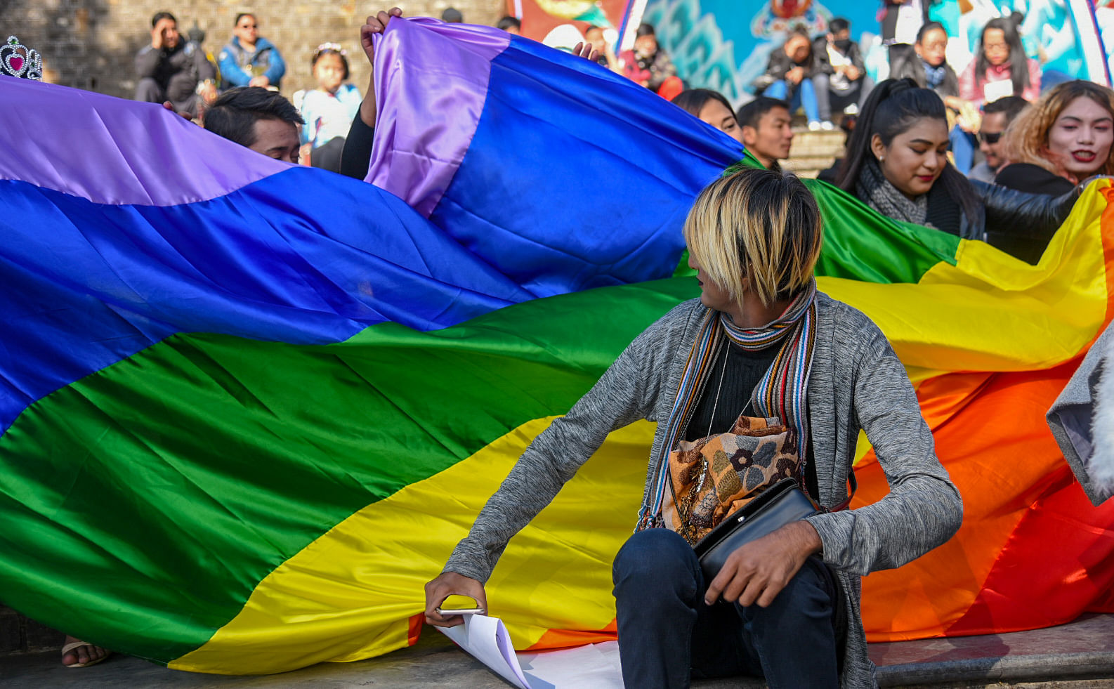 People unfurl the rainbow flag to celebrate LGBTQI+ communities.