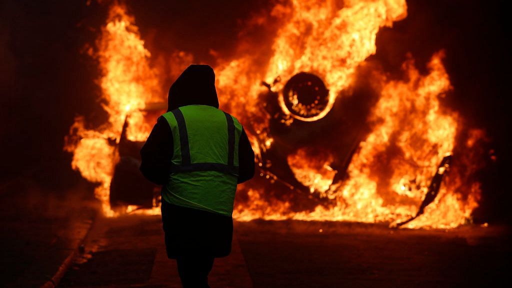 A demonstrator watches a burning car near the Champs-Elysees avenue during a demonstration.