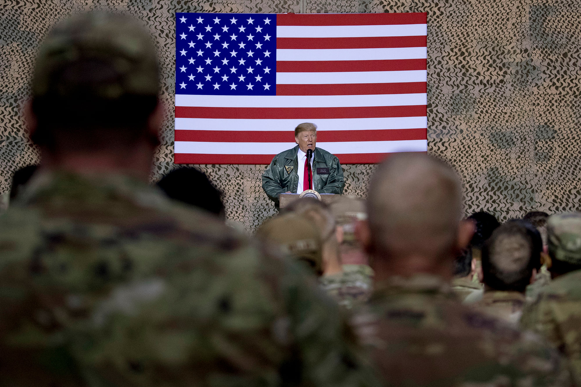 In this 26 December 2018, file photo, President Donald Trump speaks to members of the military at a hangar rally at Al Asad Air Base, Iraq.