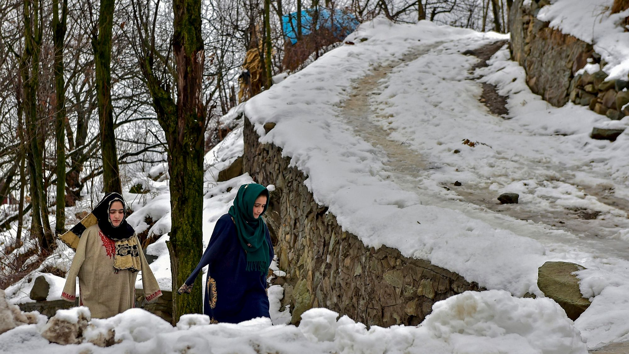 People walk on snow-covered path, on the outskirts of Srinagar.